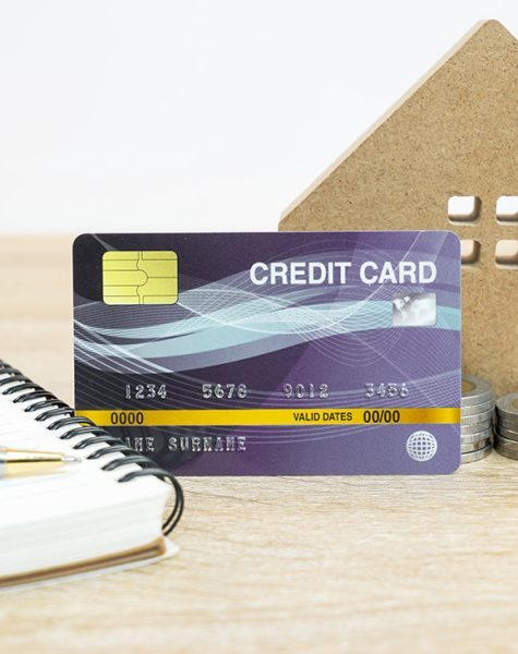 House model and and credit card on table with note pad for finance and banking concept
